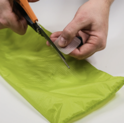 Man trimming Gear Aid SilNylon Patch to size to repair stuff sack