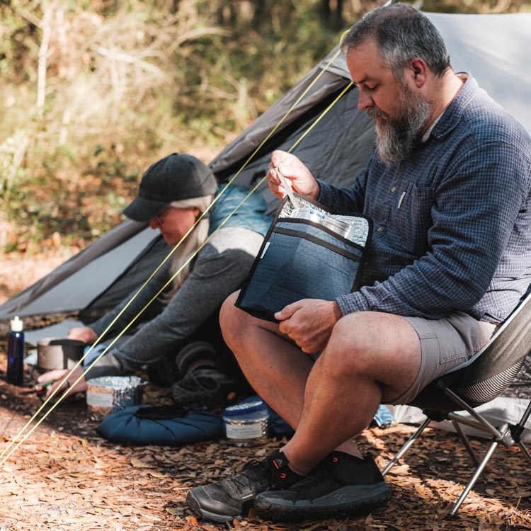 Campers cooking and eating breakfast outside tent