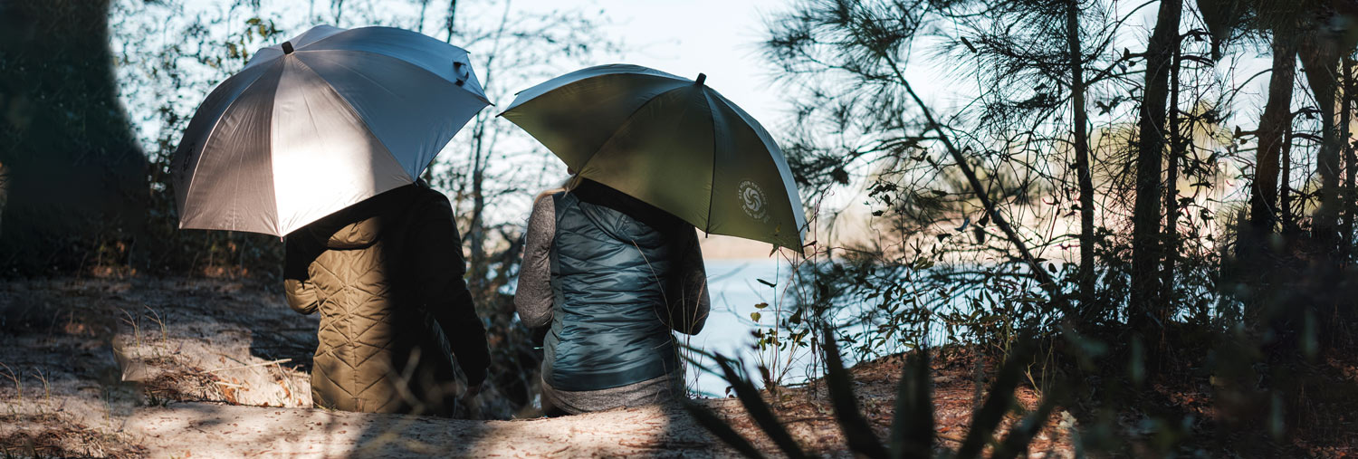 Two hikers sitting on a log with Six Moon Designs ultralight umbrellas